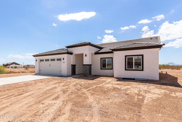 view of front facade featuring driveway, an attached garage, a tiled roof, and stucco siding