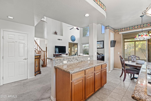 kitchen featuring plenty of natural light, light stone counters, ceiling fan, and decorative light fixtures