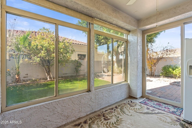 unfurnished sunroom featuring ceiling fan