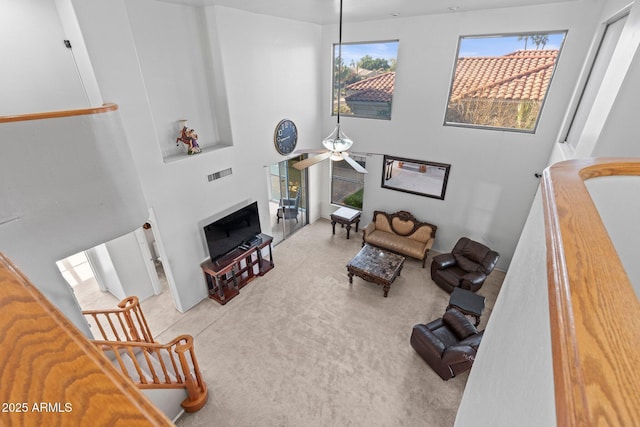 carpeted living room featuring ceiling fan and a high ceiling