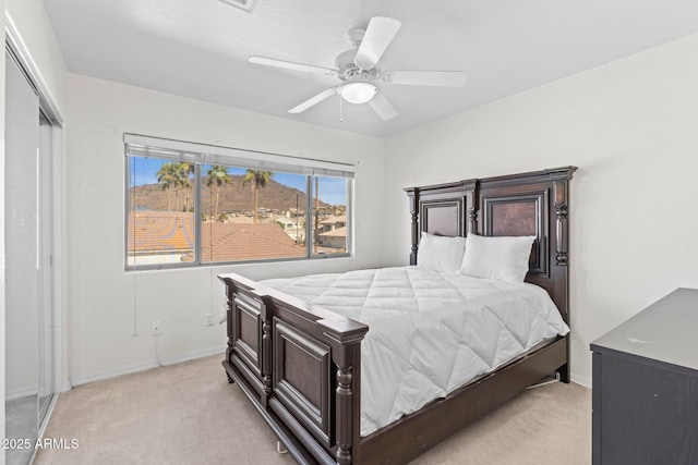 bedroom featuring light colored carpet, ceiling fan, and a closet