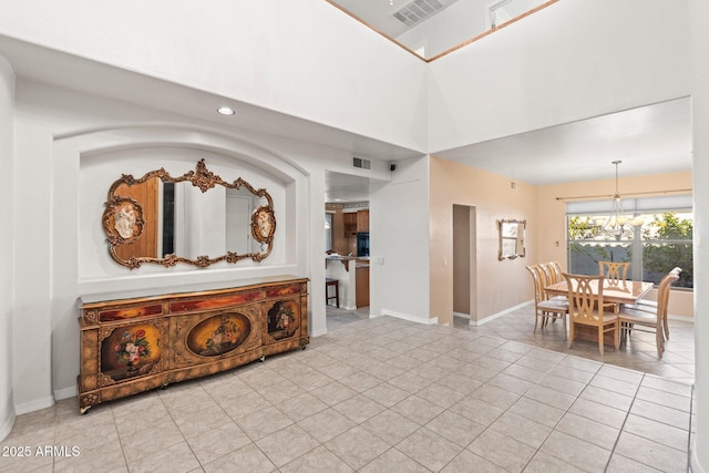 interior space featuring a chandelier, a high ceiling, and light tile patterned floors