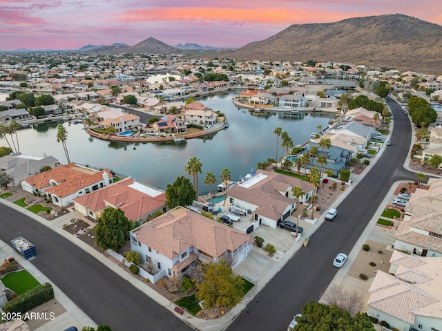 aerial view at dusk featuring a water and mountain view