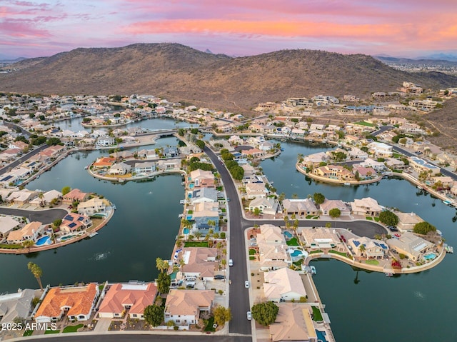 aerial view at dusk featuring a water and mountain view