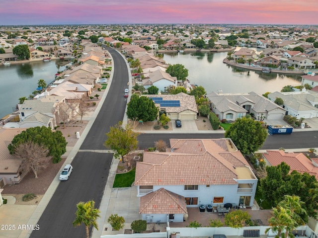 aerial view at dusk featuring a water view