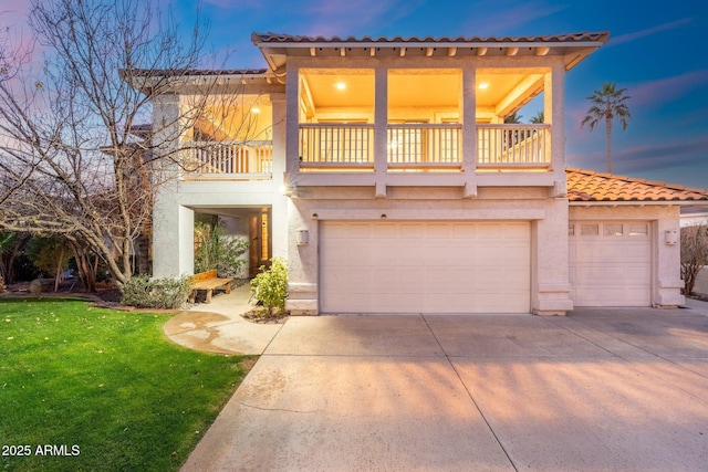 mediterranean / spanish house with a balcony, a garage, and a lawn