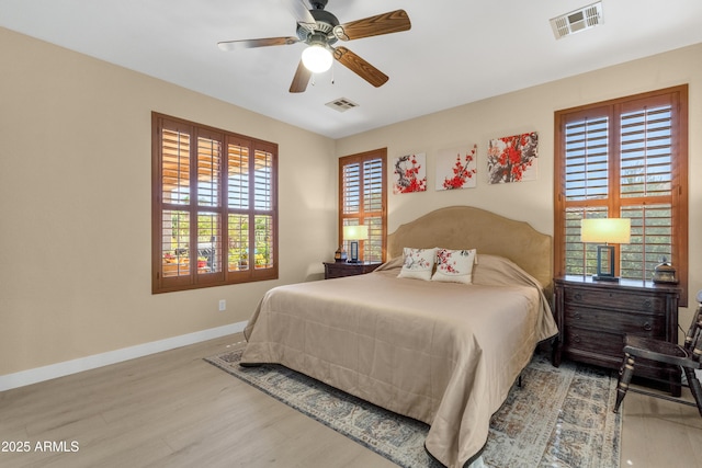 bedroom featuring ceiling fan, wood finished floors, visible vents, and baseboards