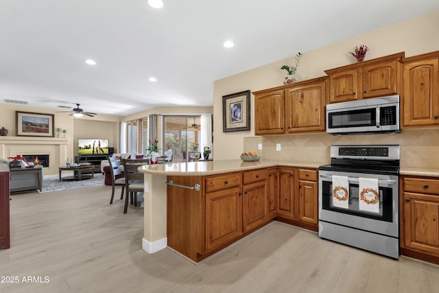 kitchen with stainless steel appliances, brown cabinets, and a peninsula