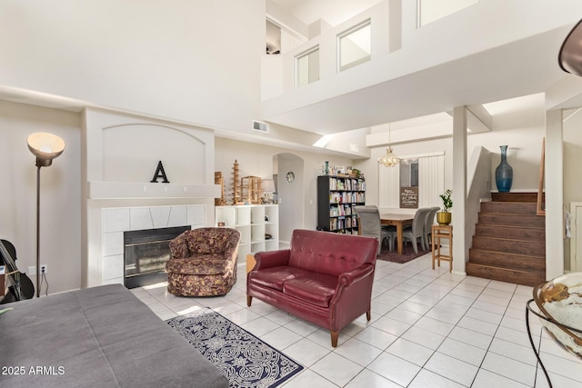 1451 E S Fork Dr, Phoenix, AZ 85048 - living room featuring a towering ceiling, light tile patterned floors, a tile fireplace, stairs, and arched walkways