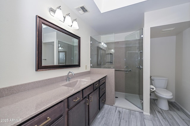 bathroom with vanity, toilet, a shower with door, and a skylight