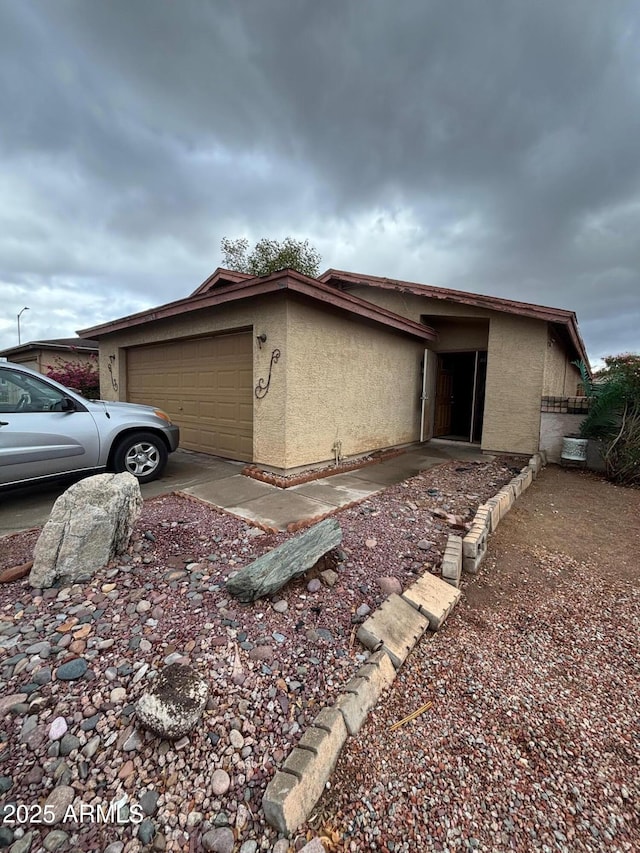 view of side of property with an attached garage and stucco siding