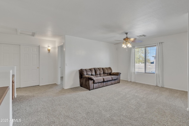 living room with visible vents, baseboards, ceiling fan, attic access, and carpet floors