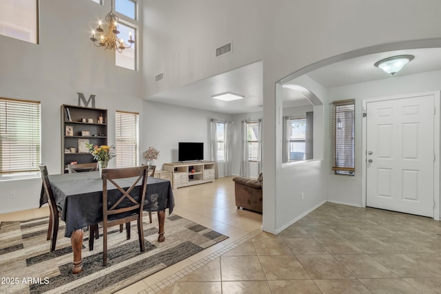 dining space featuring light tile patterned floors, arched walkways, baseboards, and visible vents
