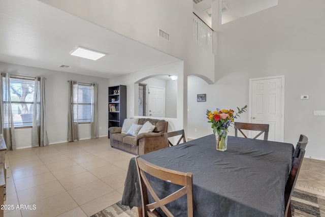dining space with light tile patterned floors, arched walkways, baseboards, and visible vents