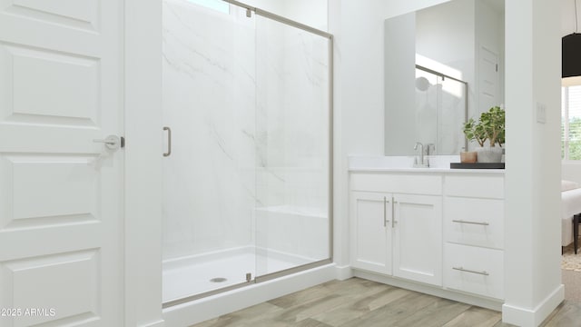 bathroom with wood finished floors, a stall shower, and vanity