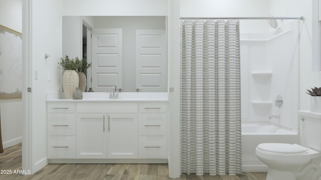 bathroom featuring wood finished floors, shower / bathtub combination with curtain, vanity, and toilet