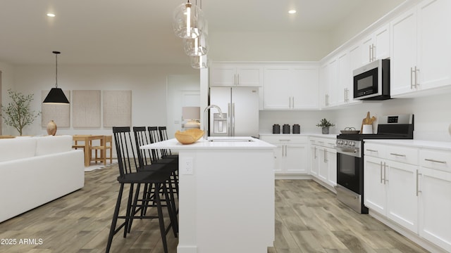 kitchen with stainless steel range with gas cooktop, white refrigerator with ice dispenser, light wood-type flooring, a kitchen island with sink, and white cabinetry