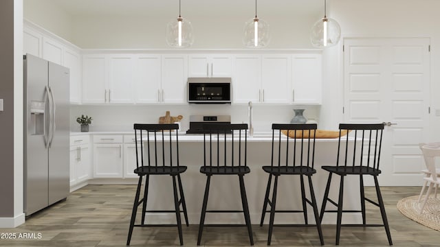 kitchen featuring stainless steel appliances, white cabinets, light wood-style floors, a kitchen breakfast bar, and a kitchen island