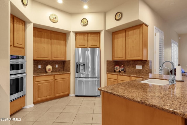 kitchen featuring dark stone countertops, sink, backsplash, and appliances with stainless steel finishes