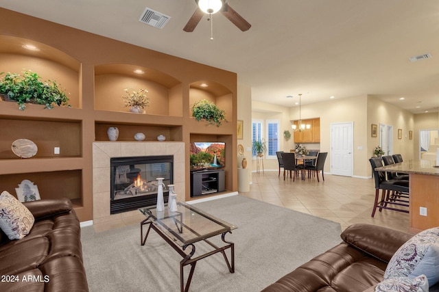 living room with tile floors, built in features, ceiling fan with notable chandelier, and a fireplace