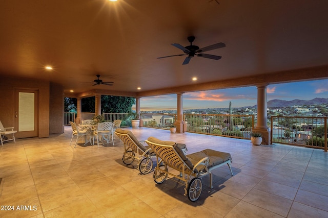 patio terrace at dusk featuring ceiling fan and a mountain view