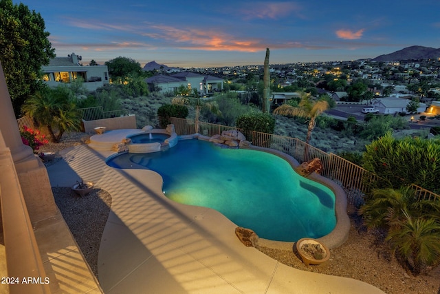 pool at dusk with an in ground hot tub