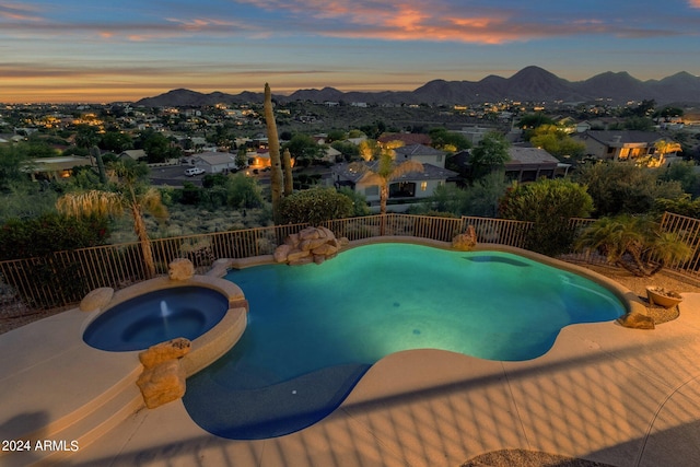 pool at dusk with an in ground hot tub and a mountain view