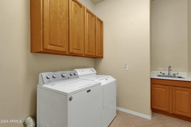 clothes washing area with cabinets, sink, washing machine and dryer, and light tile floors