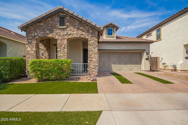 view of front facade with stone siding, decorative driveway, stucco siding, an attached garage, and a tile roof