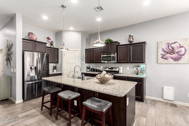 kitchen featuring light wood-style floors, a sink, dark brown cabinets, and stainless steel appliances