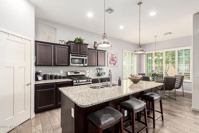 kitchen with a sink, stainless steel appliances, light wood-style flooring, and dark brown cabinets