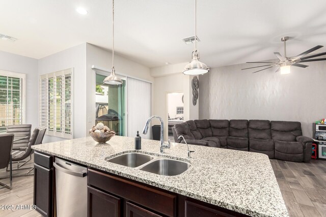 kitchen featuring stainless steel dishwasher, visible vents, open floor plan, a sink, and light wood finished floors