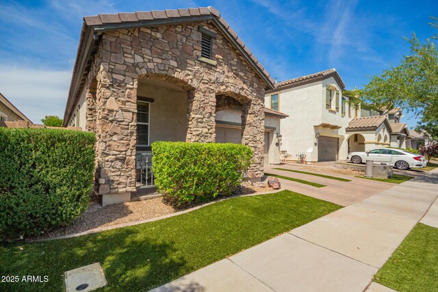 view of front of property featuring a tile roof, stone siding, a garage, stucco siding, and concrete driveway