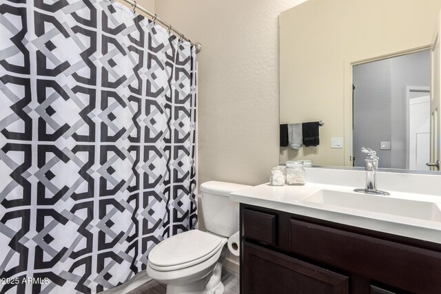 full bathroom featuring vanity, a textured wall, a shower with shower curtain, and toilet