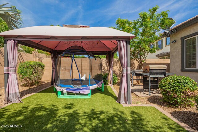 view of patio featuring grilling area, a gazebo, a fenced backyard, and a trampoline