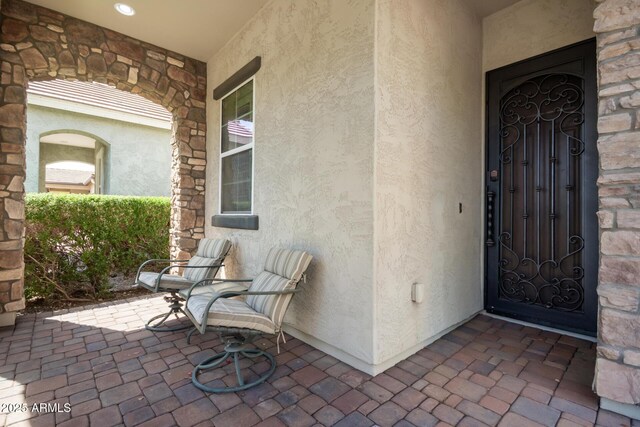 property entrance featuring stucco siding and stone siding