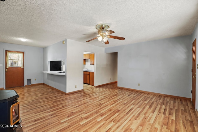 unfurnished living room with a textured ceiling, light hardwood / wood-style floors, and ceiling fan