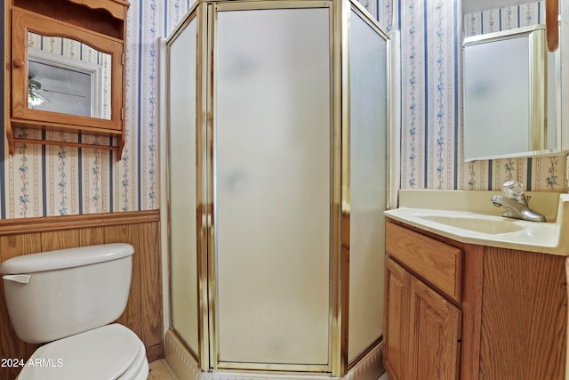 bathroom with a shower with door, vanity, and toilet