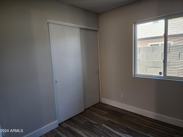 unfurnished bedroom with a closet and dark wood-type flooring