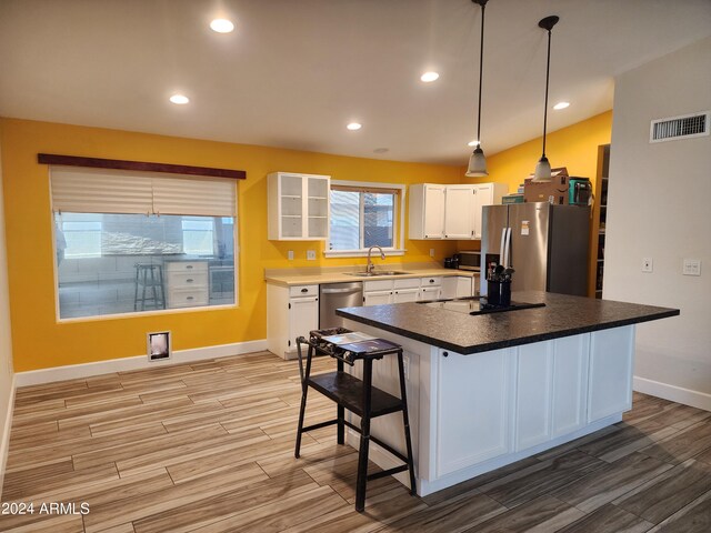 kitchen featuring appliances with stainless steel finishes, white cabinets, a center island, light hardwood / wood-style flooring, and sink