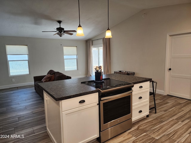 kitchen featuring hanging light fixtures, vaulted ceiling, electric stove, white cabinets, and a center island