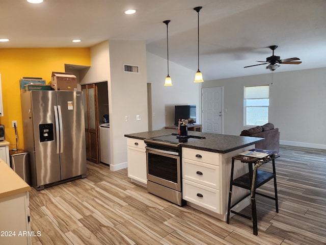 kitchen with appliances with stainless steel finishes, white cabinetry, lofted ceiling, a center island, and ceiling fan