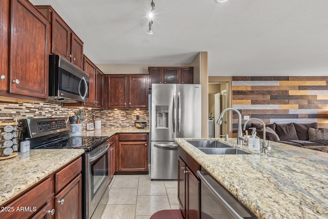 kitchen with sink, light stone counters, light tile patterned floors, stainless steel appliances, and backsplash