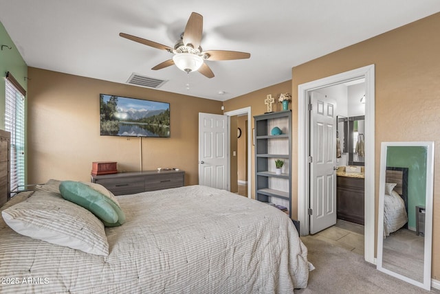 bedroom with light colored carpet, ceiling fan, and ensuite bathroom