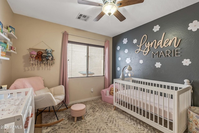 bedroom featuring a nursery area, ceiling fan, and carpet