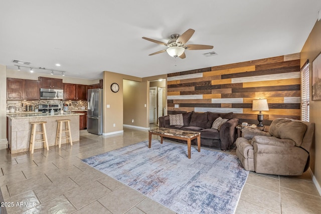 tiled living room with ceiling fan and wood walls