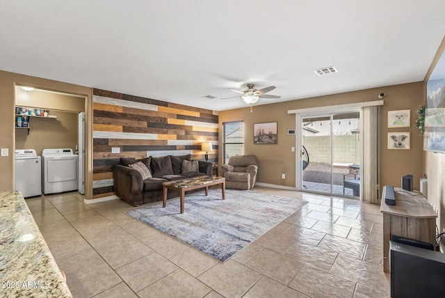 living room featuring ceiling fan, independent washer and dryer, and wood walls