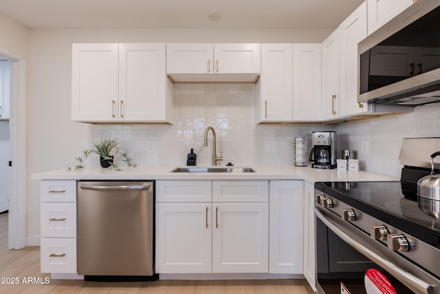 kitchen with backsplash, stainless steel appliances, white cabinets, and sink