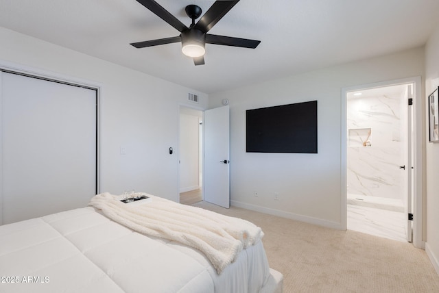 bedroom with a closet, light carpet, connected bathroom, and ceiling fan