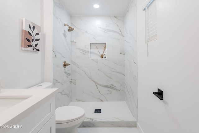 bathroom featuring tiled shower, vanity, and toilet